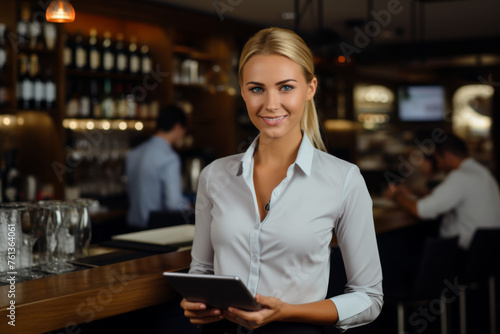 Woman is standing at bar with tablet in her hand