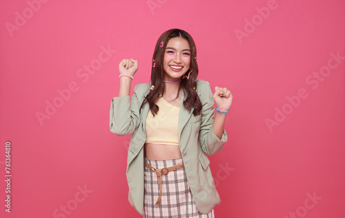 Happy ecstatic cheerful asian woman fist up raise win gesture isolated on pink copy space background.