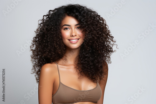 Woman with curly hair is smiling and wearing brown bra