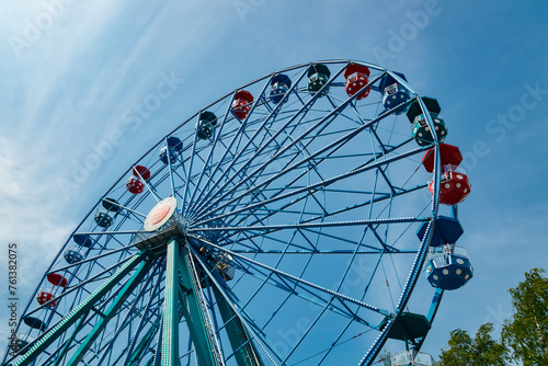 Colorful ride ferris wheel in motion in amusement park on sky background.