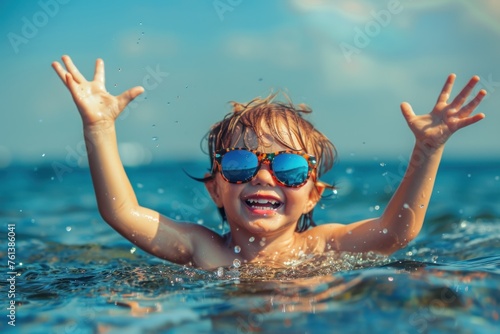 A happy child in sunglasses swims in the sea