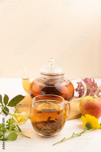 Red tea with herbs in glass teapot on white wooden. Top view, selective focus.