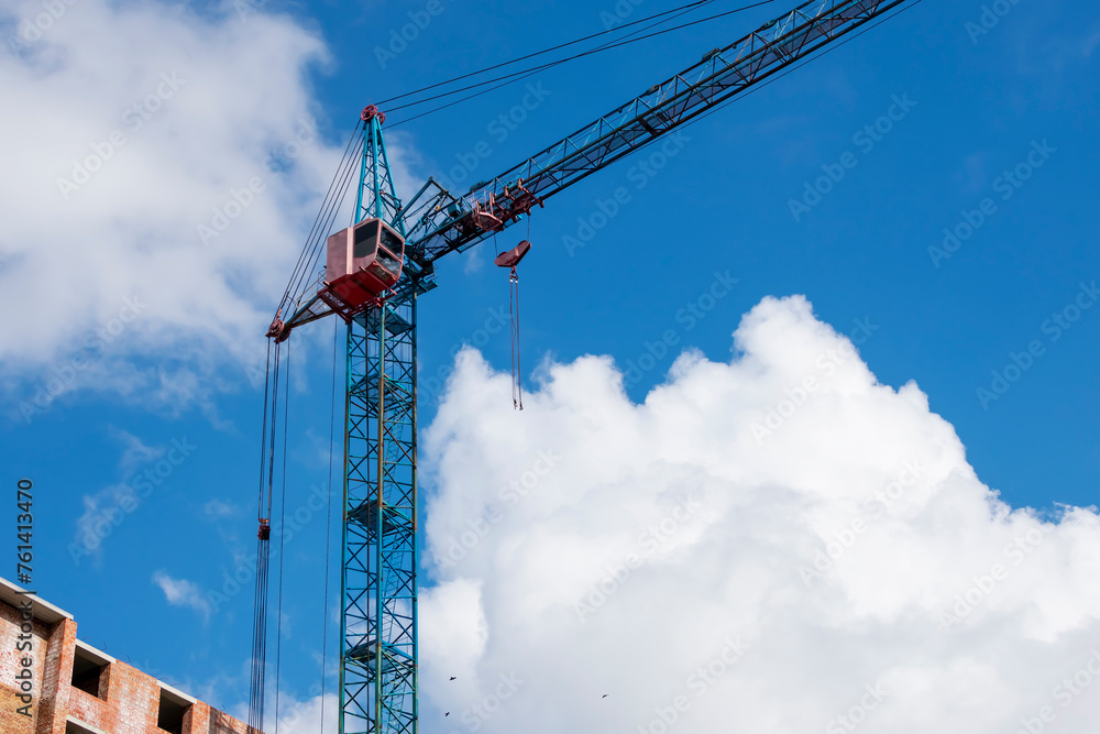 Construction crane against the background of the sky and white clouds. Construction crane against the background of the sky and white clouds.