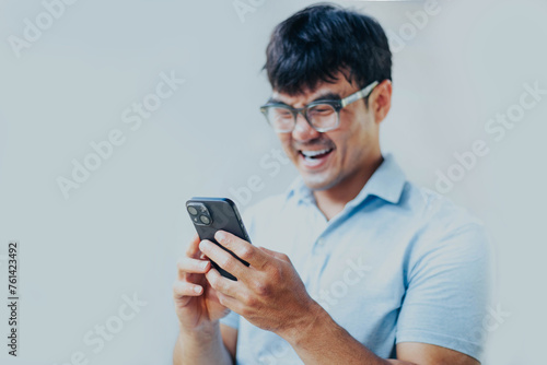 adult asian man using mobile, cell phone.young male person.posing smiling laughing look excited surprised thinking positive happy.empty,copy space for text advertising.grey background © panitan