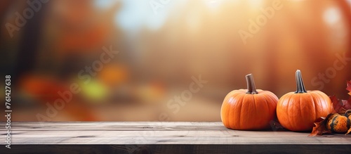 Two orange pumpkins and colorful leaves are displayed on a rustic wooden table, creating a natural foods still life scene photo