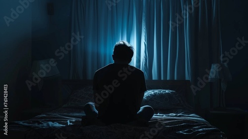 Lonely man silhouette sitting on the bed feeling depressed and stressed in the dark bedroom,