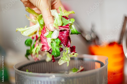 Woman washing salad leaves in centrifuge spinner.  Healthy lunch preparation in kitchen at home. Keto concept. photo