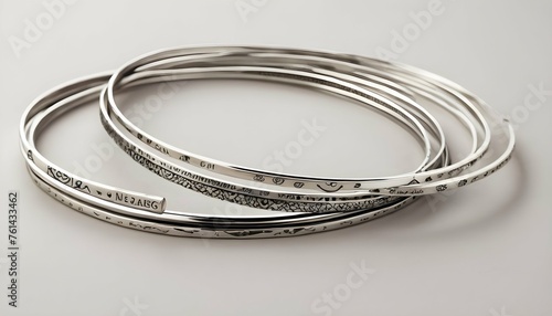 A Stack Of Slim Silver Bangles Engraved With Celes