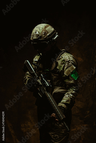 An enigmatic Latin American soldier enveloped in darkness stands with his rifle, showcasing a silhouette of readiness photo