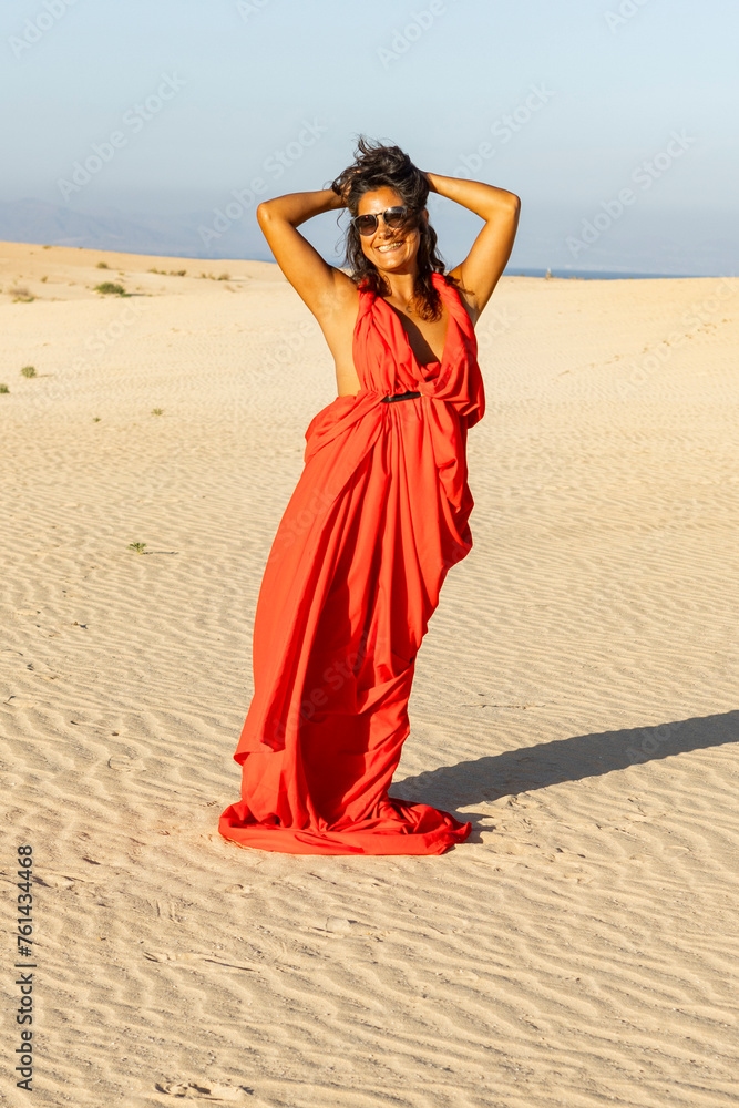 Woman in flowing red dress enjoys sunshine in desert Woman in flowing red dress enjoys sunshine in desert