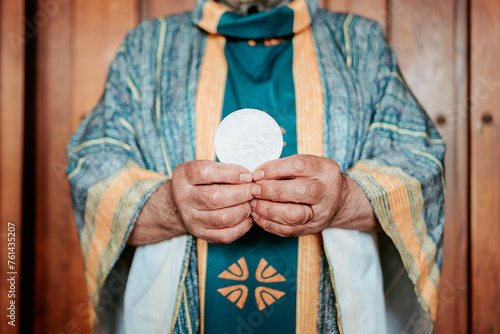 Close-up of anonymous priest's hands presenting the Eucharistic host, a sacred symbol in the Christian Holy Communion photo