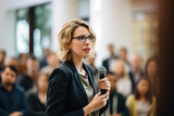 Focused professional woman speaking into a microphone at a conference.