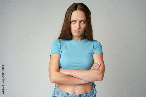 Portrait of sad displeased offended young woman in blue T-shirt on gray background photo