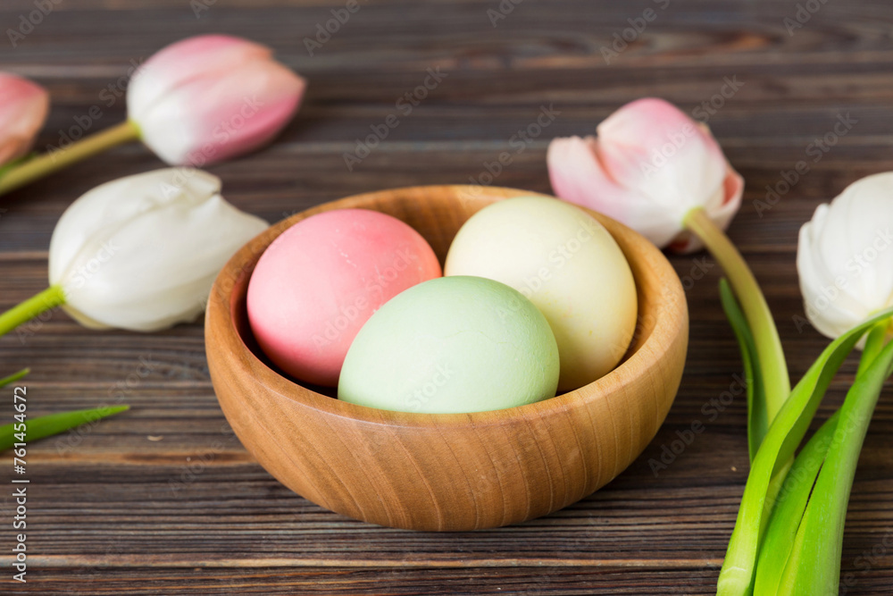Happy Easter composition. Easter eggs in basket on colored table with yellow Tulips. Natural dyed colorful eggs background with copy space Happy Easter composition. Easter eggs in basket on colored table with yellow Tulips. Natural dyed colorful eggs background with copy space