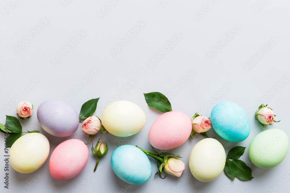 Happy Easter. Easter eggs on colored table with yellow roses. Natural dyed colorful eggs background top view with copy space Happy Easter. Easter eggs on colored table with yellow roses. Natural dyed colorful eggs background top view with copy space