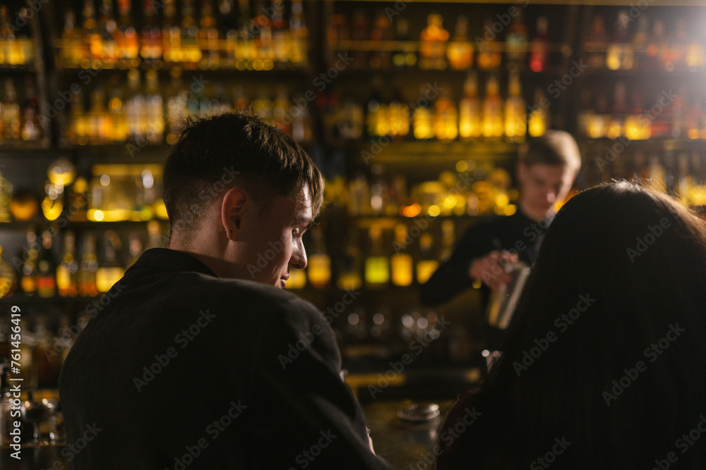Man and woman relax in nightclub waiting for alcoholic drink. Experienced bartender serves visitors making cocktail at bar counter