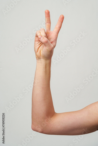 Male hand showing two fingers on gray background