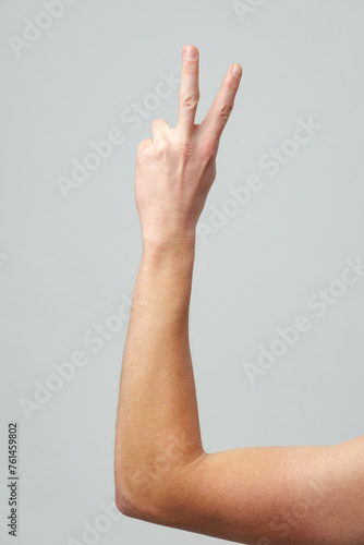 Male hand showing two fingers on gray background