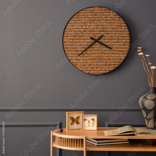 Minimalist composition of living room interior with wooden desk, stylish clock, vase with dried flowers, books, gray wall with stucco and personal accessories. Home decor. Template. © FollowTheFlow