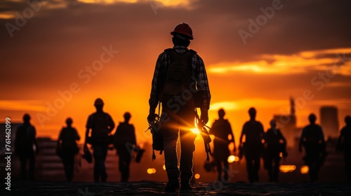 a group of workers on a construction site, with engineering infrastructure and business people silhouetted against industrial buildings © anwel
