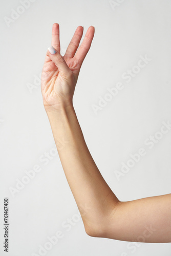 Female hand showing three fingers against white background
