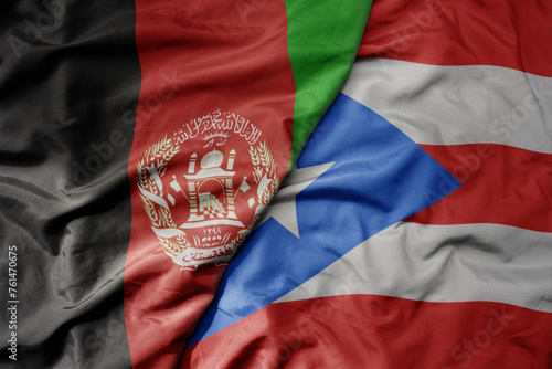 big waving national colorful flag of puerto rico and national flag of afghanistan.