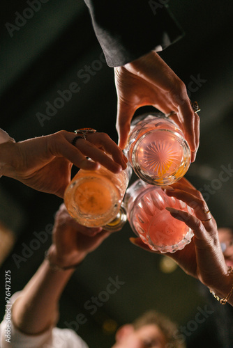 Group of mates cheers to celebrate day of meeting together. Friends drink cocktails and enjoy spending time in nightclub