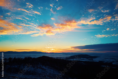 Sunset in mountains. Sun dips behind mountain peaks with golden light. Beautiful nature landscape © Lazy_Bear