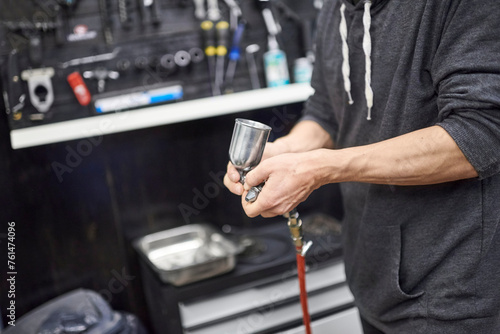 Unrecognizable hispanic worker preparing a spray paint gun in his bike workshop to airbrush a bicycle.