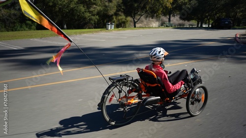 Tableau sur toile Elderly senior woman riding recumbent tricycle e-bike on a path on a sunny day in a park