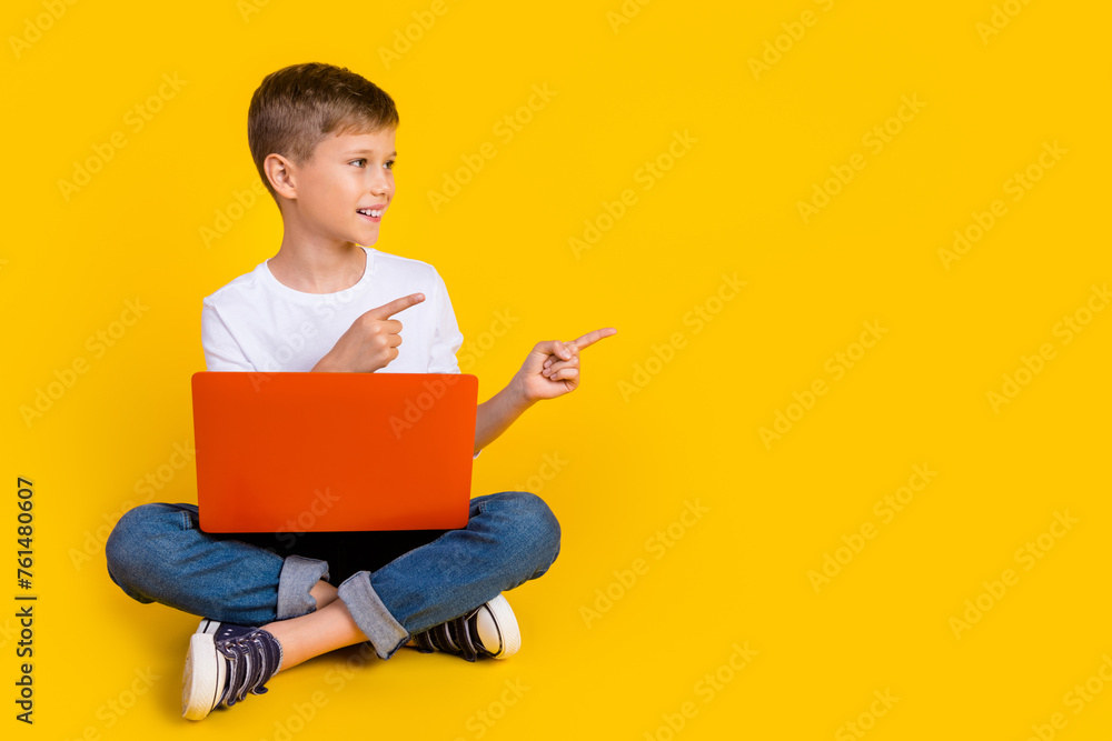 Full length photo of dreamy cute boy wear shirt studying gadget showing two fingers empty space isolated yellow color background