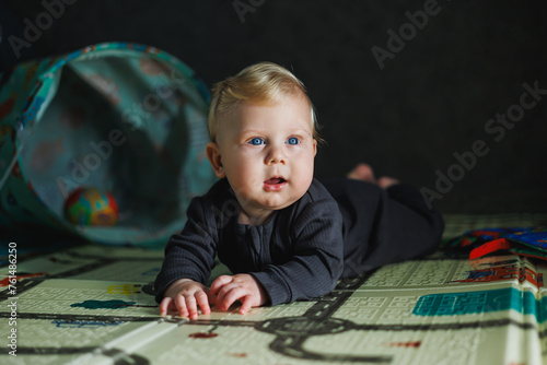 A little boy of 6 months lies on a mat and plays with toys. self-development of the baby.