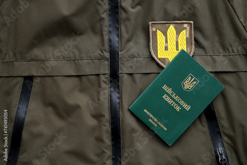 Military token or army ID ticket lies on green ukrainian military uniform indoors close up photo