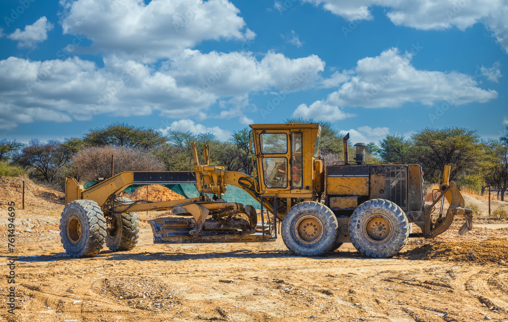 Obraz premium yellow grader digging the earth on a construction site at a diamond mine