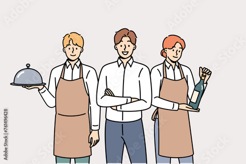 Restaurant waiters and administrators are ready to serve guests, want to have lunch or dinner. Male manager of cafe or lounge bar trains waiters to work in catering and horeca industry