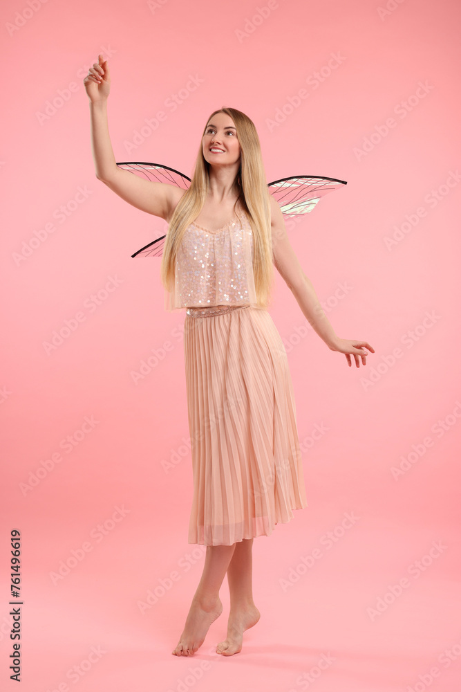 Beautiful girl in fairy costume with wings on pink background