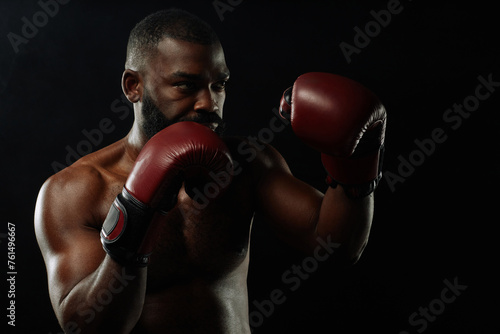 Dramatic low light shot of African American boxer in fight stance on black background