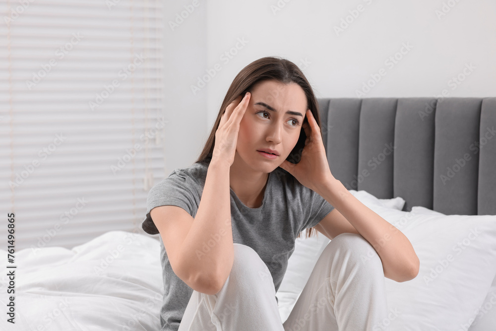 Sad woman suffering from headache on bed indoors Sad woman suffering from headache on bed indoors