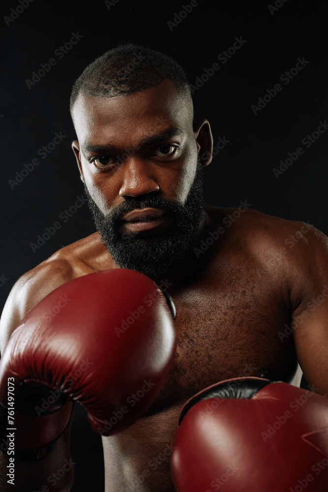 Vertical portrait of tough African American man looking at camera and wearing boxing gloves
