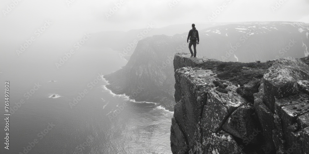 A person standing on a cliff looking out over a body of water. Suitable for travel or adventure concepts