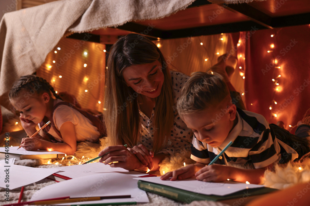 Mother and her children drawing in play tent at home