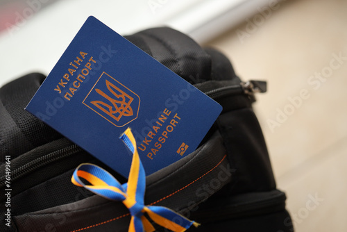 Ukrainian biometrical passport on black touristic backpack with ukrainian ribbon close up