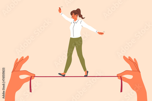 Businesswoman takes risks, walking thin tightrope in hands of employer, demonstrating ability to balance while achieving goal. Successful girl in business clothes shows balance skills photo