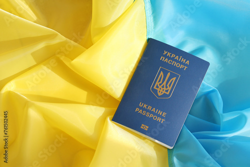 One Ukrainian biometrical passport on folded waving flag of Ukraine country close up photo