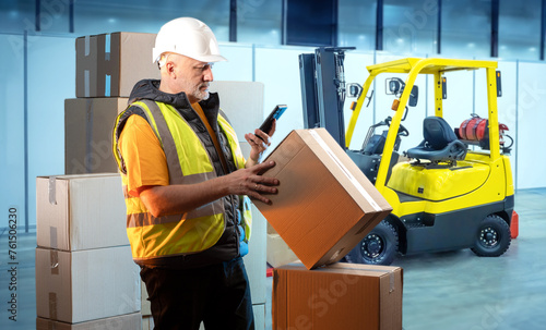 Warehouse Operator Scanning Packages with Handheld Device Beside Yellow Forklift