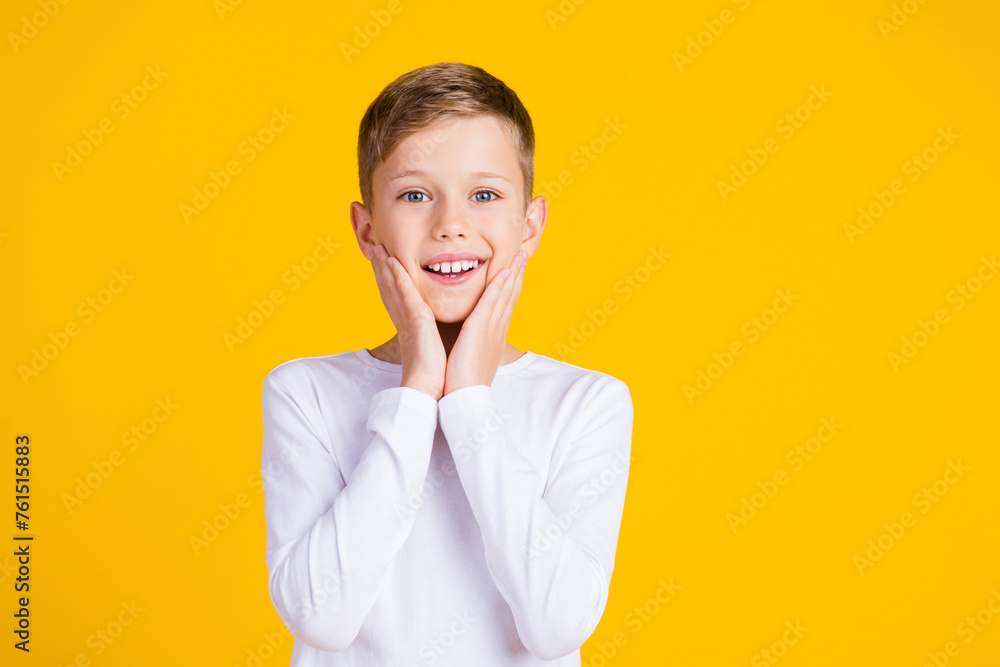 Photo of excited funky kid dressed white shirt smiling arms cheeks empty space isolated yellow color background Photo of excited funky kid dressed white shirt smiling arms cheeks empty space isolated yellow color background