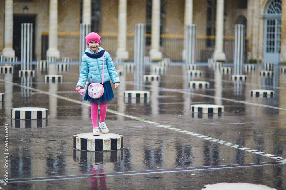 Adorable preschooler girl playing in Palais Royal garden on a rainy day. Child having fun in Paris, France. Happy kid playing outdoors.