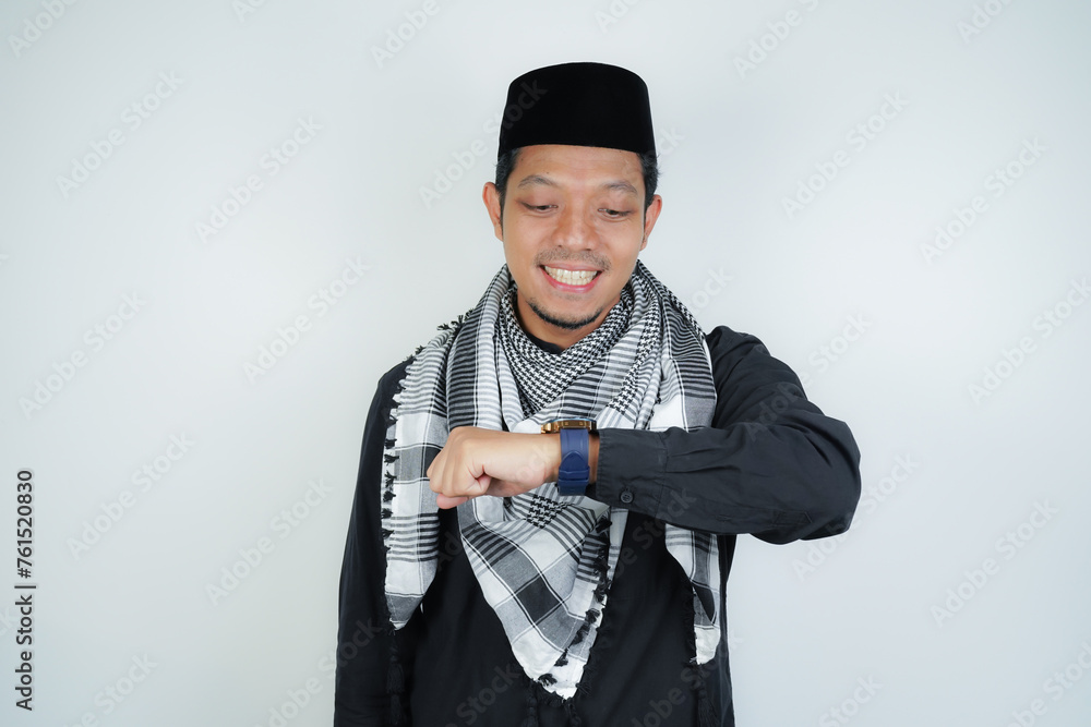 Asian Muslim man wearing Arab turban sorban excited face expression looking at watch, wearing Arabic costume in copy space on isolated background Asian Muslim man wearing Arab turban sorban excited face expression looking at watch, wearing Arabic costume in copy space on isolated background