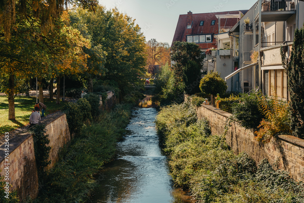 Beautiful small river with clean and clear water front of colorful autumn trees and small old town on the hill agaist nice blue and clouds sky during autumn in Europe Beautiful small river with clean and clear water front of colorful autumn trees and small old town on the hill agaist nice blue and clouds sky during autumn in Europe
