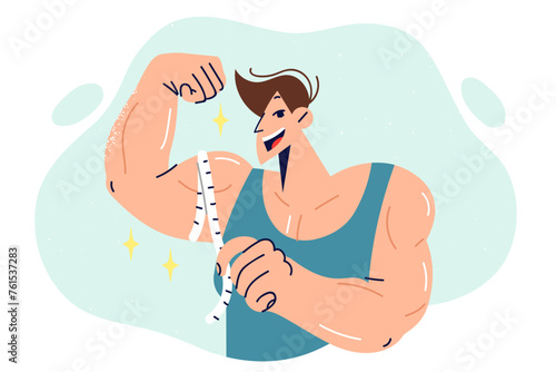 Muscular man bodybuilder showing big biceps, using measuring tape to show progress. 